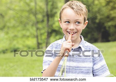 Caucasian boy eating carrot outdoors View Large Photo Image Stock Photo - Caucasian boy eating carrot outdoors. Fotosearch
