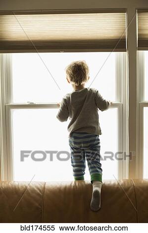 Stock Photography - Caucasian boy looking out window. Fotosearch