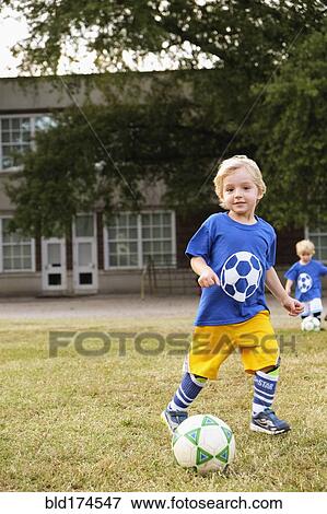 Stock Photo - Caucasian boy playing soccer in field. Fotosearch