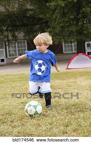 Caucasian boy playing soccer in field View Large Photo Image Stock Photograph - Caucasian boy playing soccer in field. Fotosearch