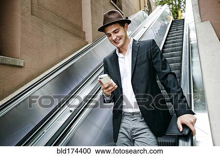 Caucasian businessman using cell phone on escalator View Large Photo Image Stock Image - Caucasian businessman using cell phone on escalator. Fotosearch