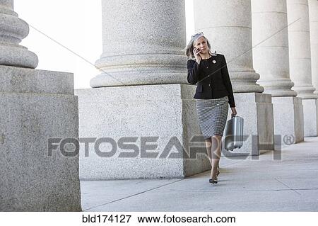 Caucasian businesswoman talking on cell phone under columns View Large Photo Image Stock Photo - Caucasian businesswoman talking on cell phone under columns. Fotosearch