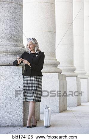 Caucasian businesswoman using cell phone under columns View Large Photo Image Stock Photography - Caucasian businesswoman using cell phone under columns. Fotosearch