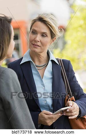 Caucasian businesswomen using cell phone outdoors View Large Photo Image Stock Photo - Caucasian businesswomen using cell phone outdoors. Fotosearch