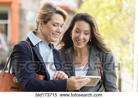 Stock Photography - Caucasian businesswomen using digital tablet outdoors. Fotosearch
