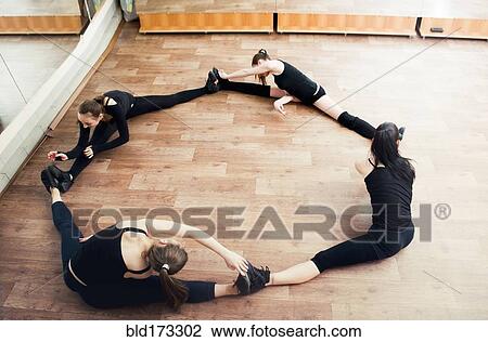 Stock Image - Caucasian dancers stretching in studio. Fotosearch