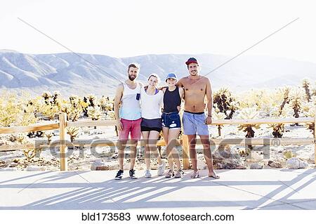 Stock Image - Caucasian friends smiling on desert path. Fotosearch