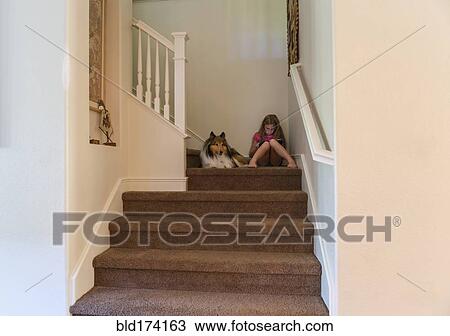 Stock Image - Caucasian girl and dog sitting on stairs. Fotosearch