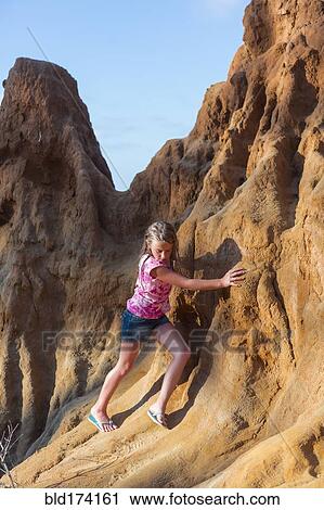 Stock Image - Caucasian girl climbing rock formations. Fotosearch