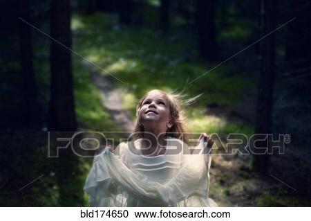 Stock Image - Caucasian girl playing in forest. Fotosearch