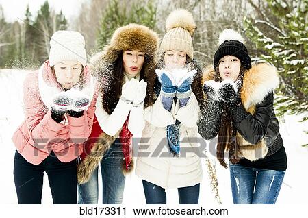 Stock Image - Caucasian girls blowing snow from hands. Fotosearch