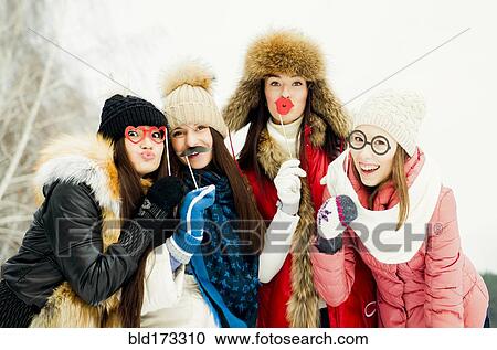 Stock Image - Caucasian girls playing with disguises in snow. Fotosearch