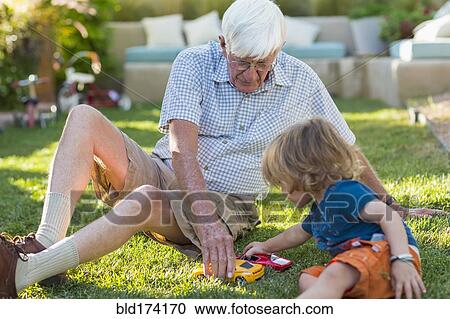Stock Image - Caucasian grandfather and grandson playing on lawn. Fotosearch