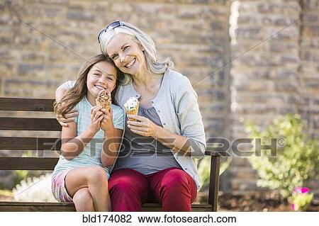 Stock Image - Caucasian grandmother and granddaughter eating ice cream. Fotosearch