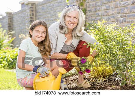Stock Photo - Caucasian grandmother and granddaughter gardening in backyard. Fotosearch