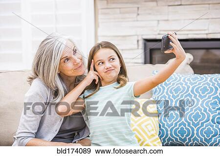 Stock Photo - Caucasian grandmother and granddaughter taking selfie with cell phone. Fotosearch