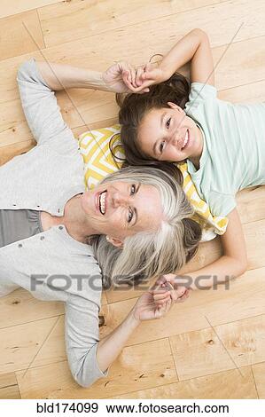 Stock Photo - Caucasian grandmother and granddaughter laying on floor. Fotosearch
