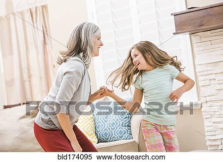 Stock Photography - Caucasian grandmother and granddaughter dancing in living room. Fotosearch