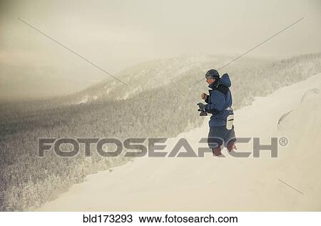 Stock Image - Caucasian hiker standing on snowy mountain. Fotosearch