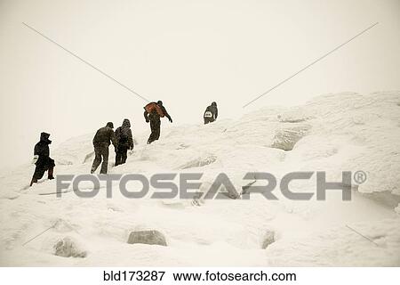 Stock Photo - Caucasian hikers climbing snowy mountain. Fotosearch