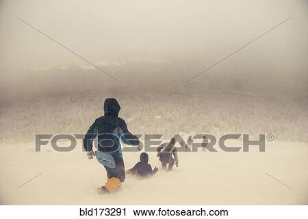 Stock Image - Caucasian hikers walking on snowy hill. Fotosearch