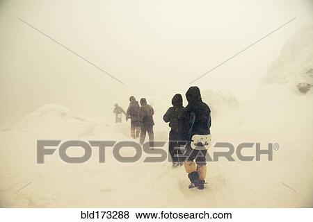 Stock Photo - Caucasian hikers walking on snowy path. Fotosearch