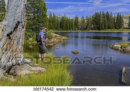 Stock Image - Caucasian man admiring remote lake. Fotosearch