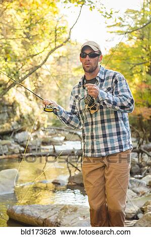 Stock Photo - Caucasian man fishing in forest steam. Fotosearch