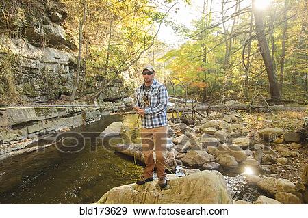 Caucasian man fishing in forest steam View Large Photo Image Stock Photo - Caucasian man fishing in forest steam. Fotosearch