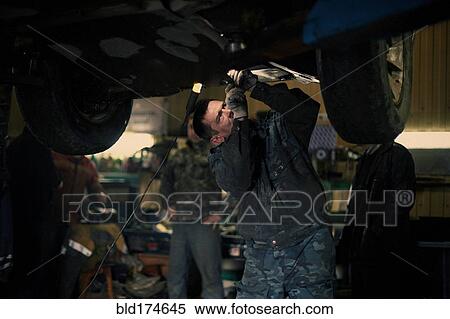 Caucasian mechanic fixing car View Large Photo Image Stock Photography - Caucasian mechanic fixing car. Fotosearch