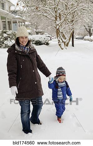 Stock Image - Caucasian mother and son walking in snow. Fotosearch