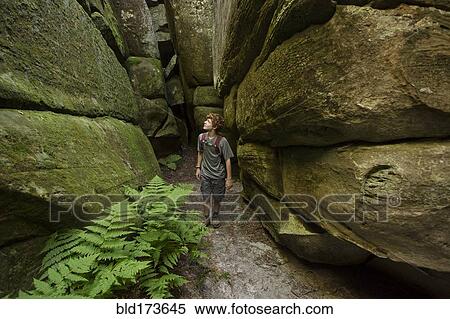 Stock Photography - Caucasian teenage boy exploring cave. Fotosearch
