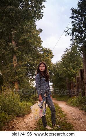 Stock Photograph - Caucasian teenage girl carrying kite on dirt road. Fotosearch
