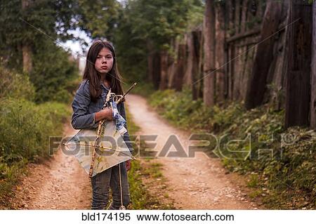 Stock Photography - Caucasian teenage girl carrying kite on dirt road. Fotosearch