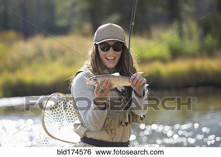 Stock Photograph - Caucasian woman displaying fishing catch. Fotosearch