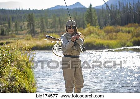 Stock Photo - Caucasian woman fishing in rural river. Fotosearch