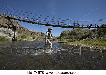 Stock Photo - Caucasian woman fishing in rural river. Fotosearch
