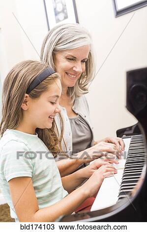 Stock Image - Caucasian woman giving student piano lessons. Fotosearch