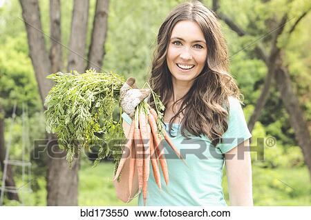 Caucasian woman holding carrots in garden View Large Photo Image Stock Image - Caucasian woman holding carrots in garden. Fotosearch