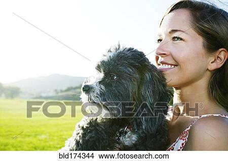 Picture - Caucasian woman holding dog outdoors. Fotosearch