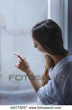 Stock Photo - Caucasian woman looking out window. Fotosearch