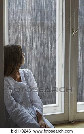 Stock Photograph - Caucasian woman looking out window. Fotosearch