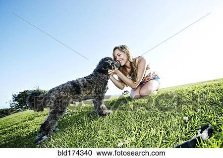 Stock Image - Caucasian woman playing with dog. Fotosearch