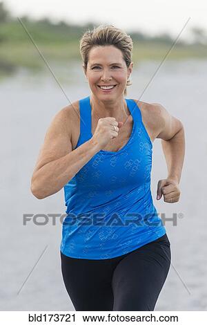 Stock Image - Caucasian woman running on beach. Fotosearch