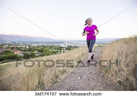 Stock Photo - Caucasian woman running on hilltop. Fotosearch