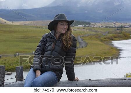 Stock Image - Caucasian woman sitting at rural river. Fotosearch
