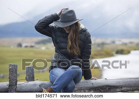 Stock Image - Caucasian woman sitting at rural river. Fotosearch
