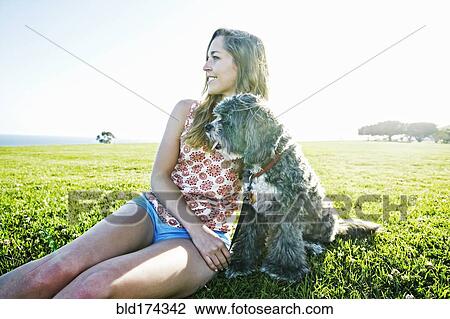 Caucasian woman sitting in field with dog View Large Photo Image Stock Image - Caucasian woman sitting in field with dog. Fotosearch