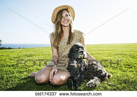 Caucasian woman sitting in field with dog View Large Photo Image Stock Photo - Caucasian woman sitting in field with dog. Fotosearch