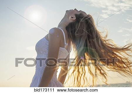 Stock Image - Caucasian woman tossing her hair outdoors. Fotosearch